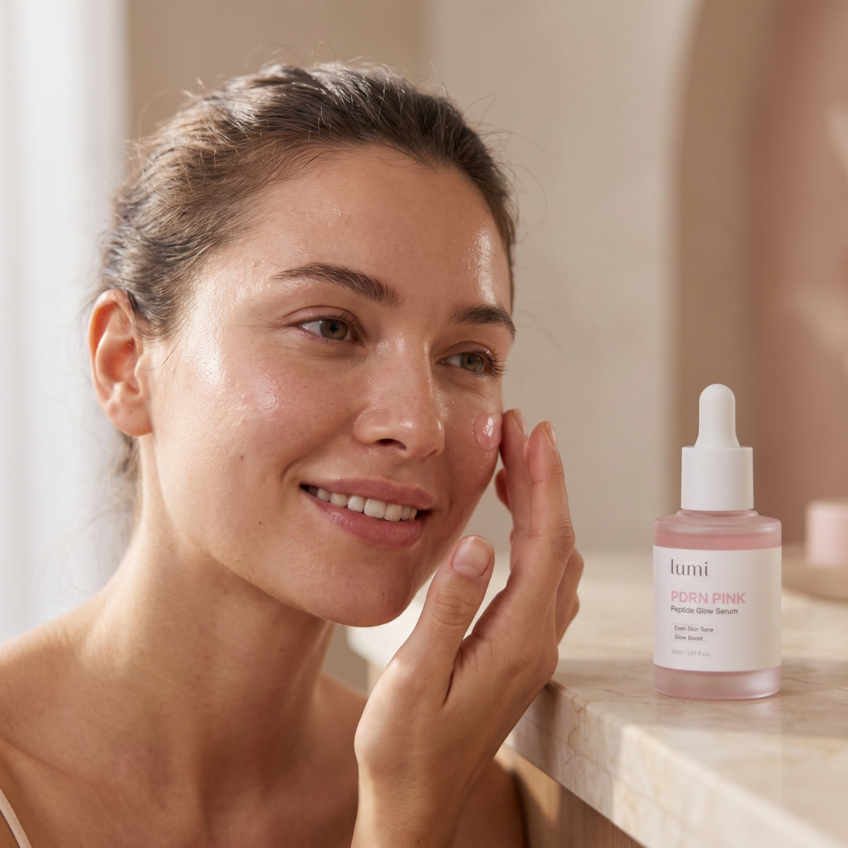 Woman smiling while applying Lumi PDRN Pink Peptide Glow Serum to her cheek with her fingertips