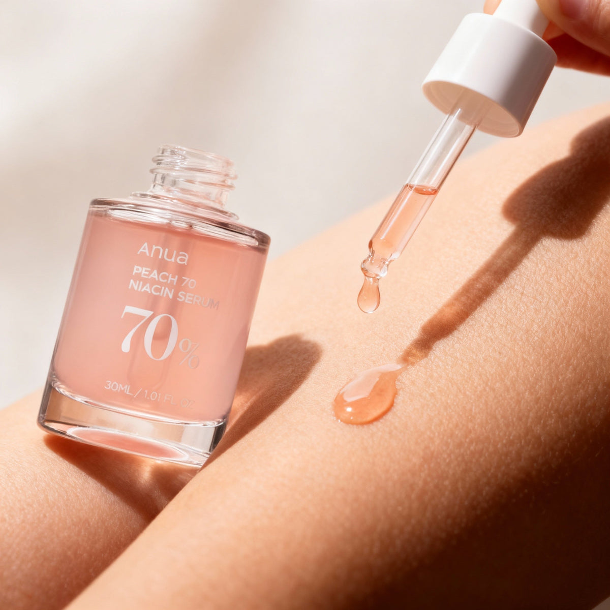 Dropper releasing a droplet of PeachGlow Niacinamide Body Serum
